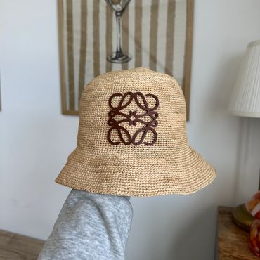 Handwoven straw bucket hat with a brown embroidered logo.