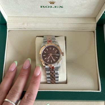 A Rolex watch with a two-tone metal band in a green and beige box.