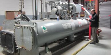 Technician inspecting a large industrial machine in a factory setting.