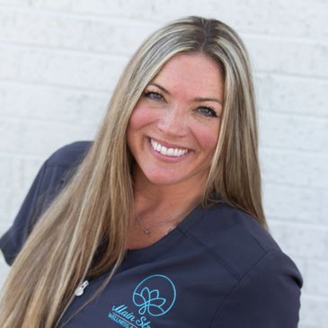 Dana massage therapist smiling by brick wall