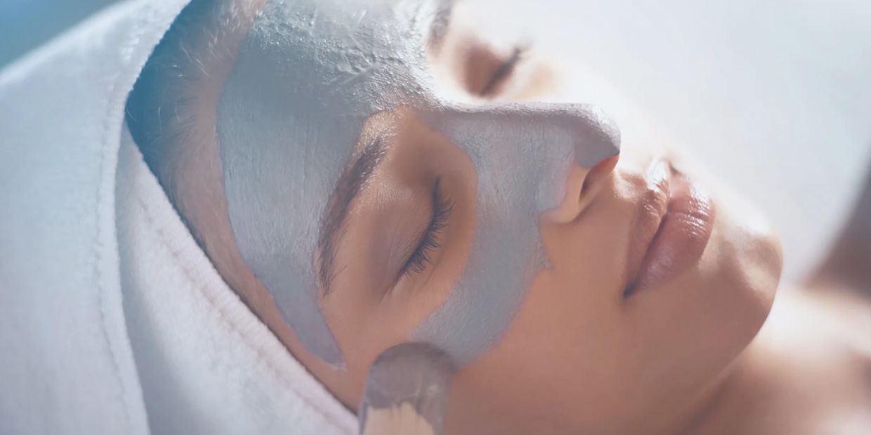 woman receiving skincare mask with brush at spa