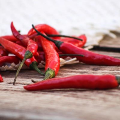 Fresh red chili peppers scattered on a rustic wooden surface.