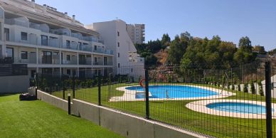 Apartment complex with a fenced pool area on a sunny day.