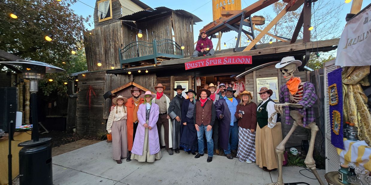 Group dressed in old western attire outside Dusty Spur Saloon.