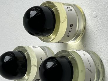 Three perfume bottles with black caps on a white surface.