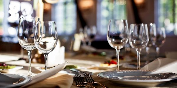 Elegant dining table set with glassware and silverware in soft lighting.