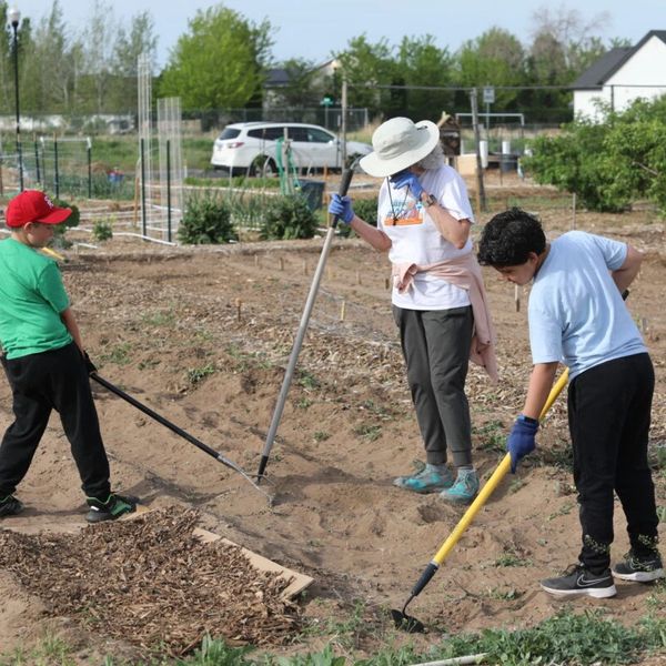 Community members and child tilling garden 