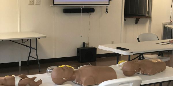 CPR training mannequins arranged on tables in a classroom.