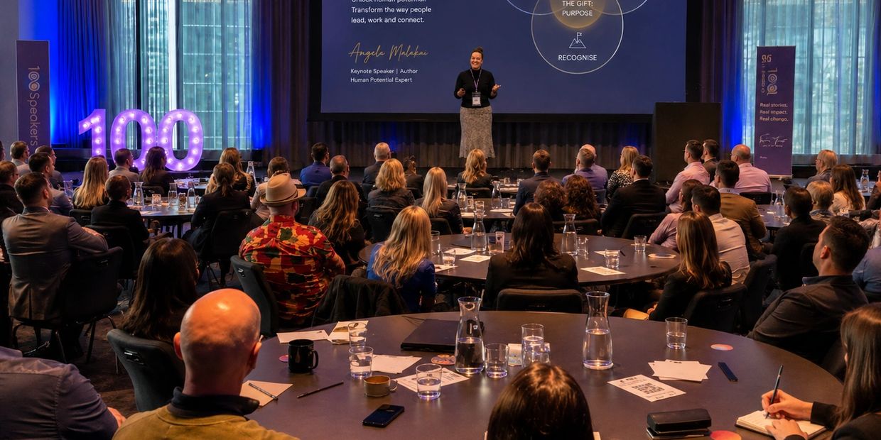 Speaker presenting to a large conference audience.