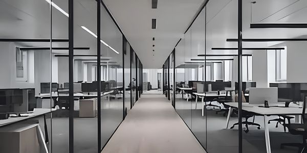 Modern office corridor with glass walls and workstations on both sides.