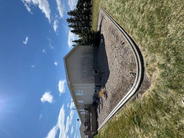 A house with a large gravel yard and a clear blue sky.