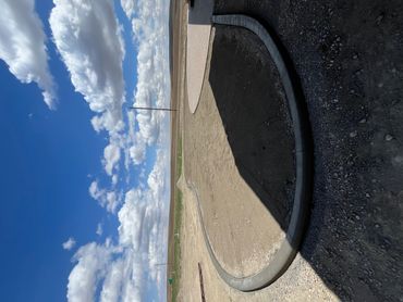 A clear sky over a curved concrete pathway in an open, flat landscape.