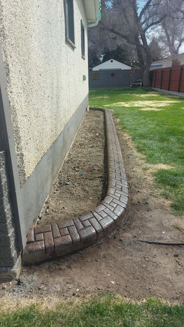 Newly installed brick border along a house garden bed.