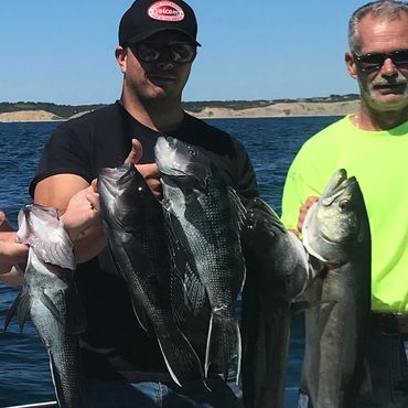 Two men displaying their large catches of fish.