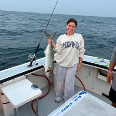 Woman holding a large fish on a boat.