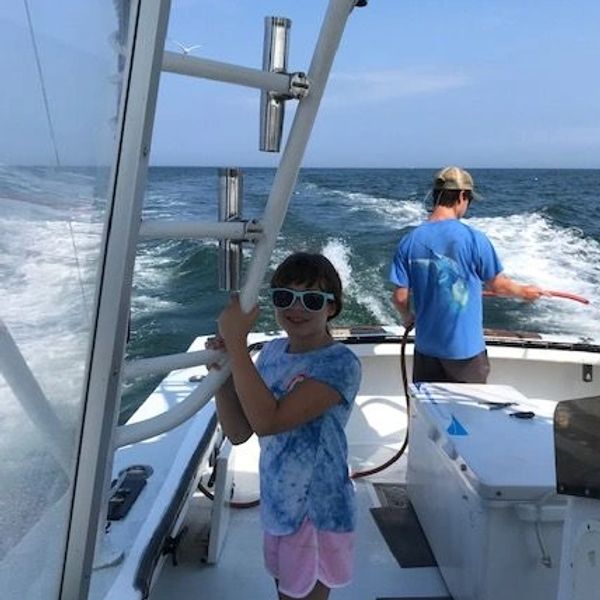 Child and adult fishing on a boat in the ocean.