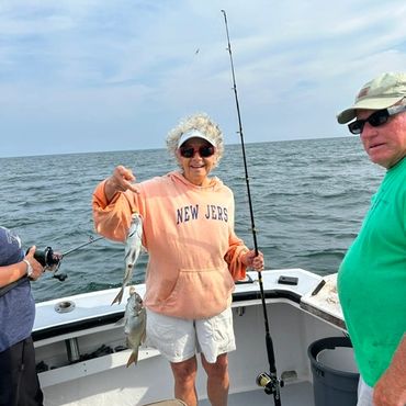 Two men on a boat holding fishing rods and fish.