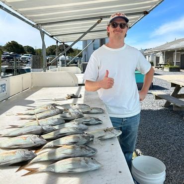 Man posing with a large catch of fish on a boat.