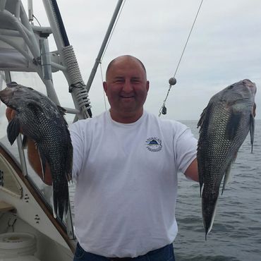 Man holding two large fish on a boat.