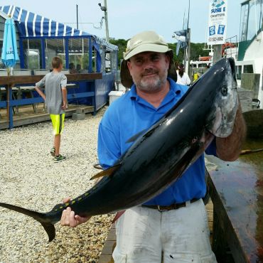 Man holding a large fish at a dock.