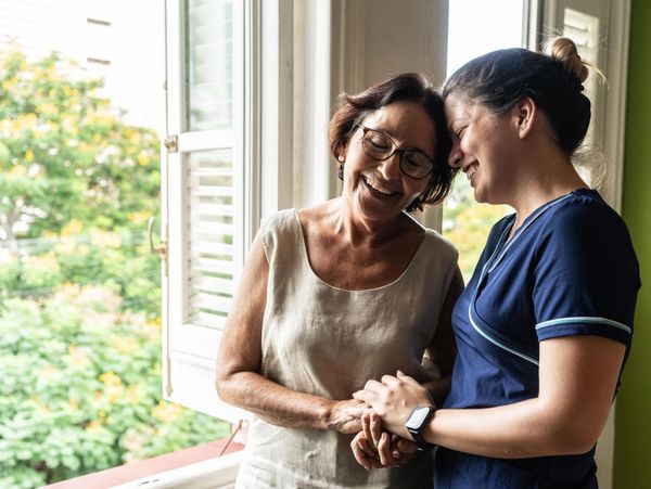 Two women sharing a joyful moment by a window.