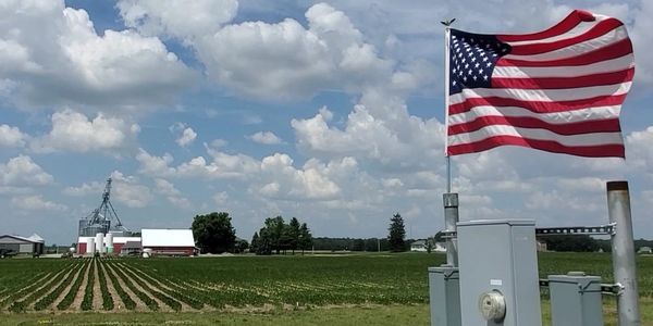 American Flag in Front of Farm Background