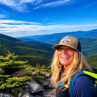 Smiling woman hiking in the mountains under a blue sky.
