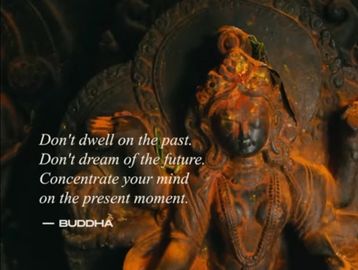 A Buddha statue with a quote about living in the present moment.