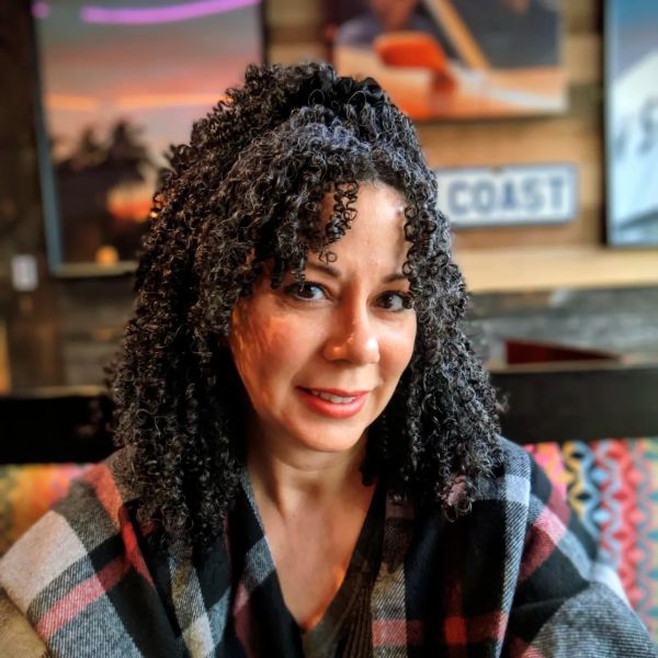 A woman with curly hair smiling indoors.