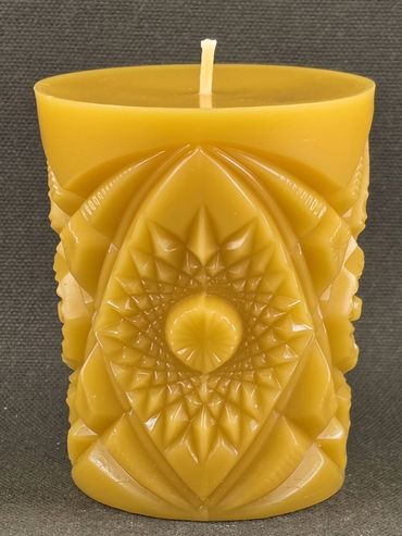 Intricately carved yellow candle with geometric and floral patterns.