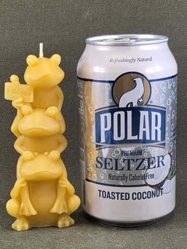 Stacked frog candle sculpture next to a can of toasted coconut seltzer.