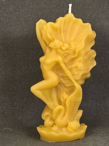 Intricately carved yellow candle featuring a nude female figure with a swan and floral details.