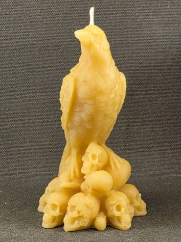 Yellow candle shaped like a bird perched on skulls.