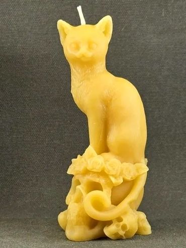A yellow cat-shaped candle with floral and skull details at the base.