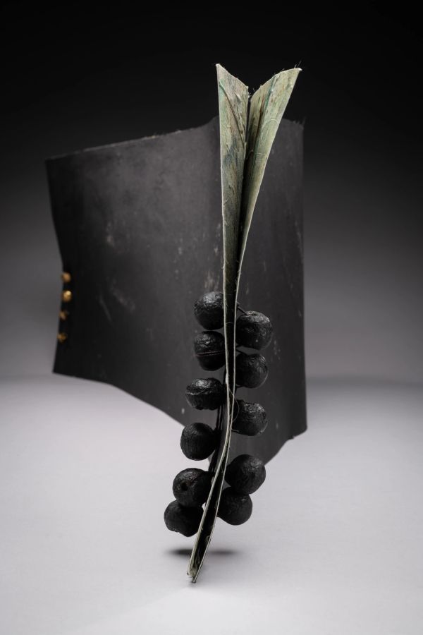 Abstract book sculpture with black spheres.