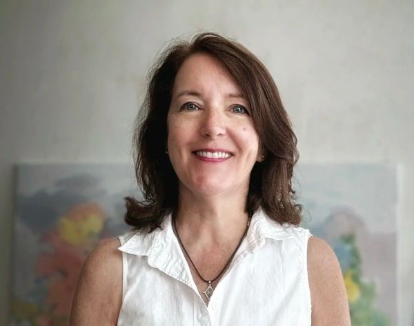 Smiling woman in white sleeveless shirt.