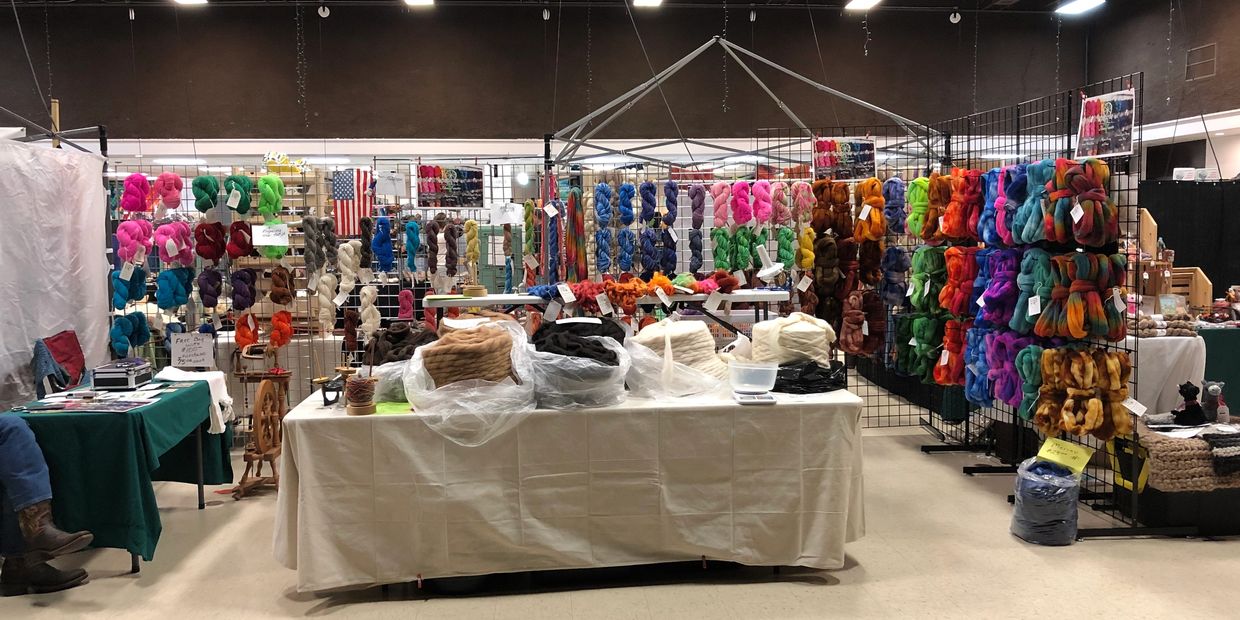 Colorful yarns and wool displayed at a craft fair booth.