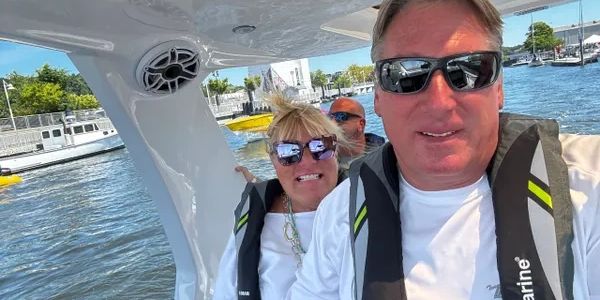 Two people wearing life jackets on a boat, smiling at the camera.