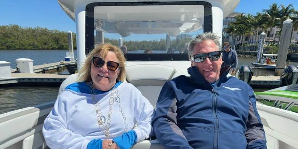 A smiling couple relaxing on a boat under sunny skies.