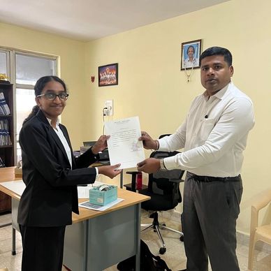Two people exchanging a certificate in an office setting.