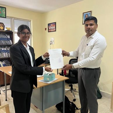 Two people exchanging a certificate in an office setting.