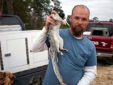 Man holding a large squirrel by its tail.
