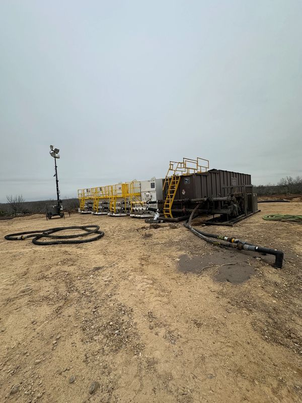 Industrial equipment on a barren dirt field under cloudy sky.