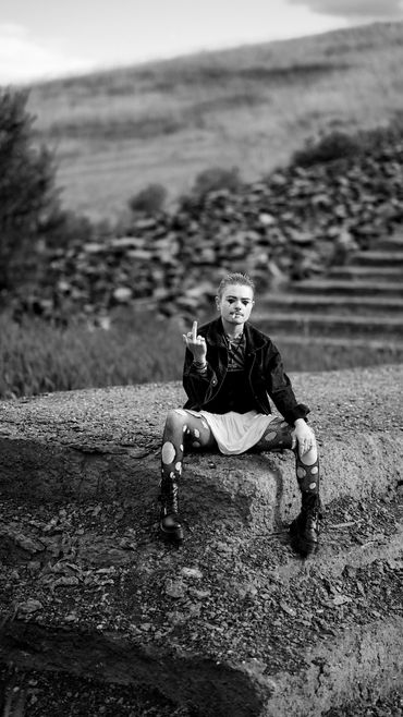 Person sitting on stone with rebellious gesture.