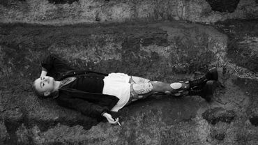 Person lying down on textured ground in black and white.