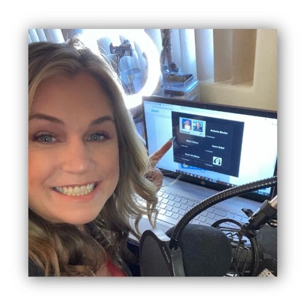 A smiling selfie of Roberta Blevins at a laptop and podcast microphone.