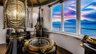 View from inside a lighthouse with navigation instruments and ocean outside.