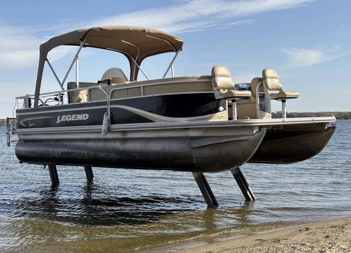 Picture of a Pontoon Boat that is docked on its sea legs at the beach.