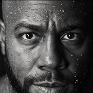 Close-up of a man's intense face with water droplets on his skin.