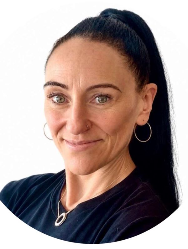 Woman with dark ponytail smiling gently.
